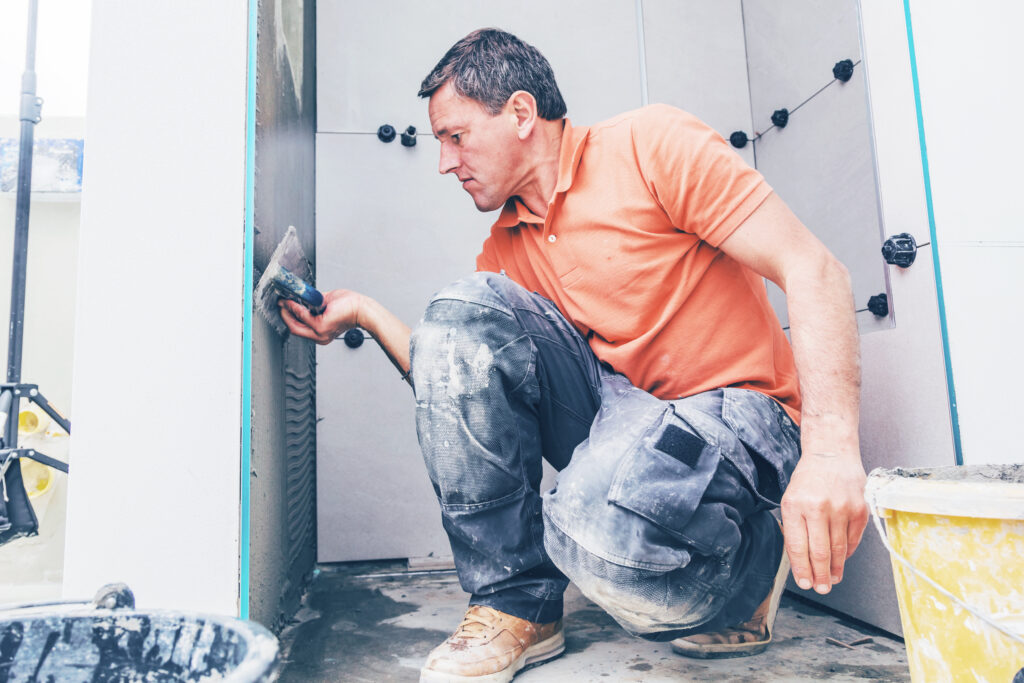 Signature worker fixing tiles on the bathroom wall